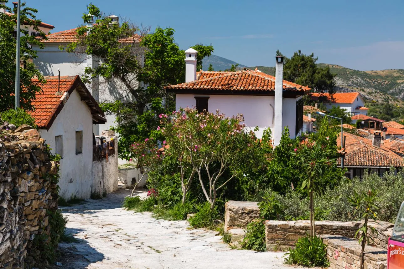 A whitewashed house with a red-tiled roof and oleanders on a cobbled street in Şirince