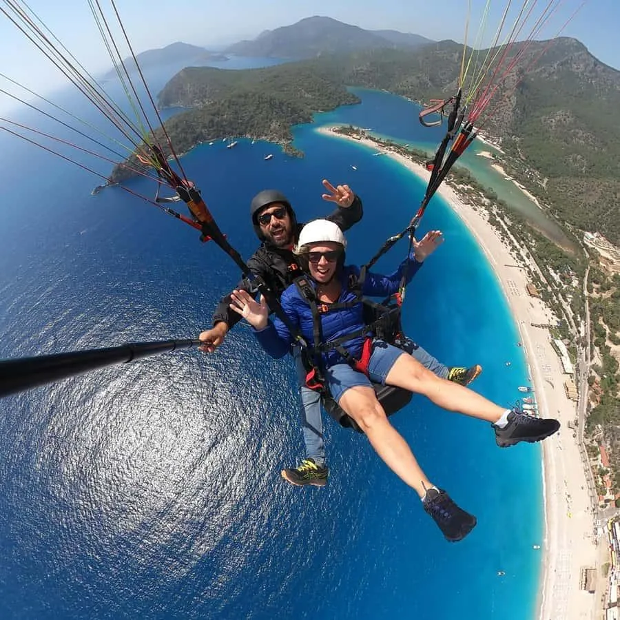 A tandem paraglider pair flying high above the Ölüdeniz lagoon