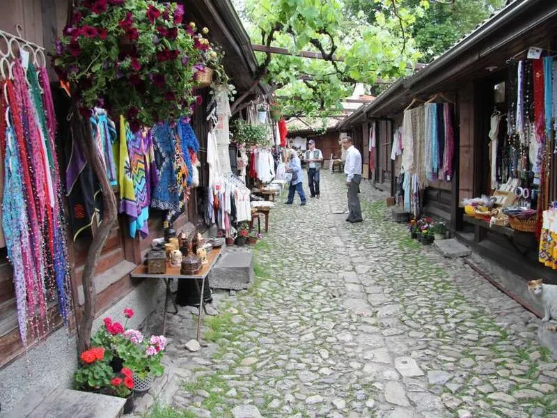 A vine-shaded cobbled bazaar lane with textiles and souvenirs for sale
