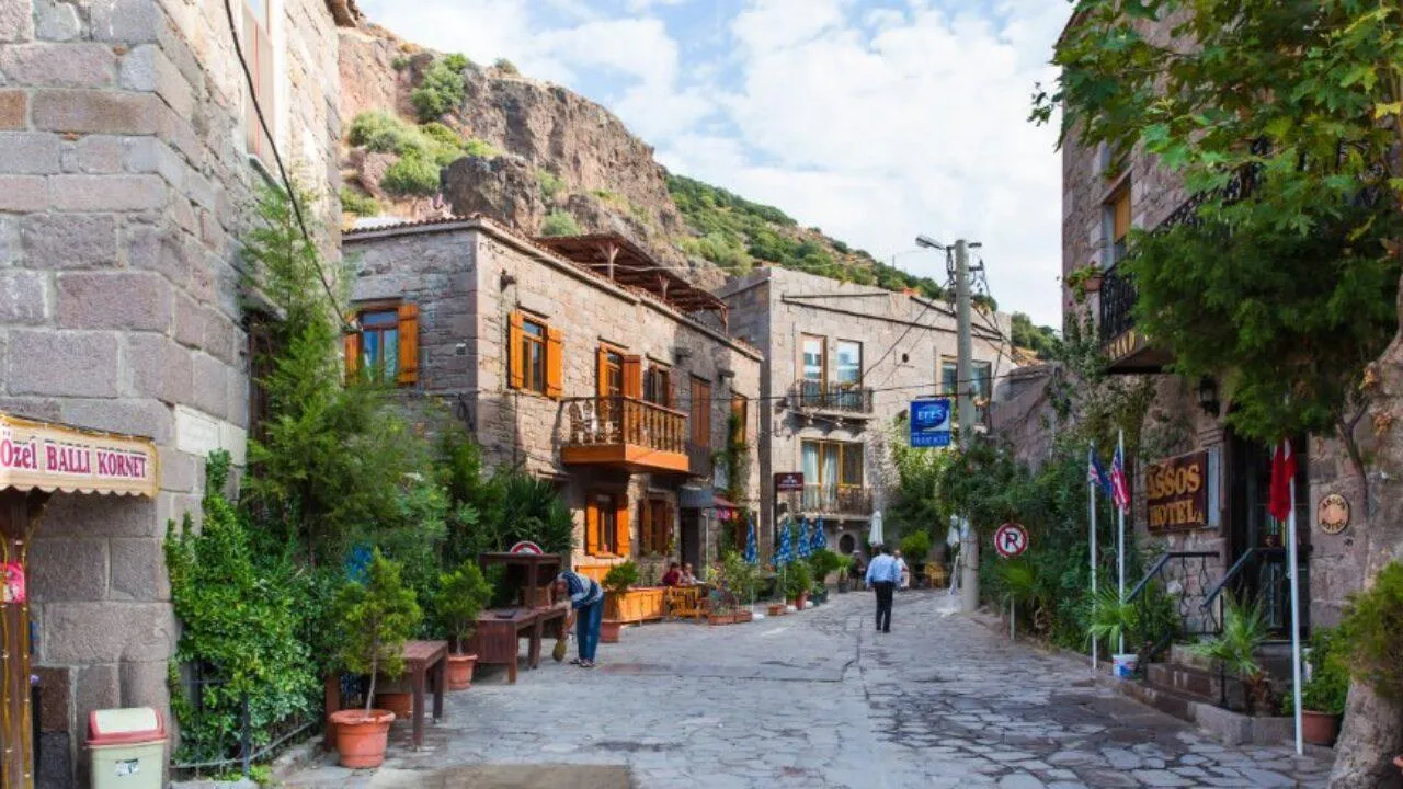 A cobbled lane in Behramkale lined with stone houses, plants and small shops