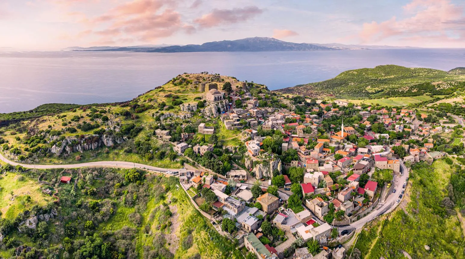 Behramkale village spread over its green hill above the sea, with the acropolis at the top