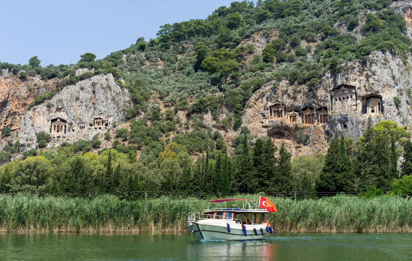A river boat with a Turkish flag below the rock-cut tombs of Kaunos