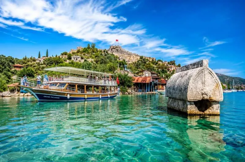 A boat and a Lycian sarcophagus standing in the clear water at Kaleköy