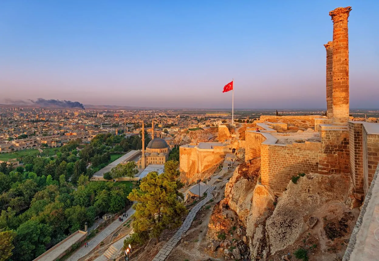 The two columns and walls of Şanlıurfa Castle above the city at sunset
