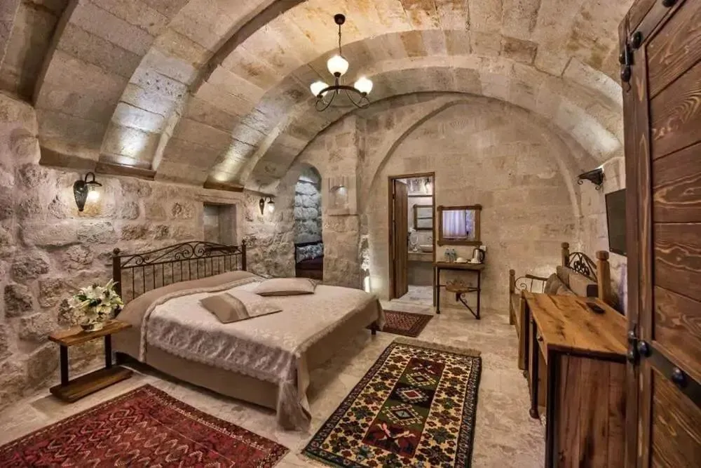 A vaulted stone cave hotel room with carpets and wooden furniture