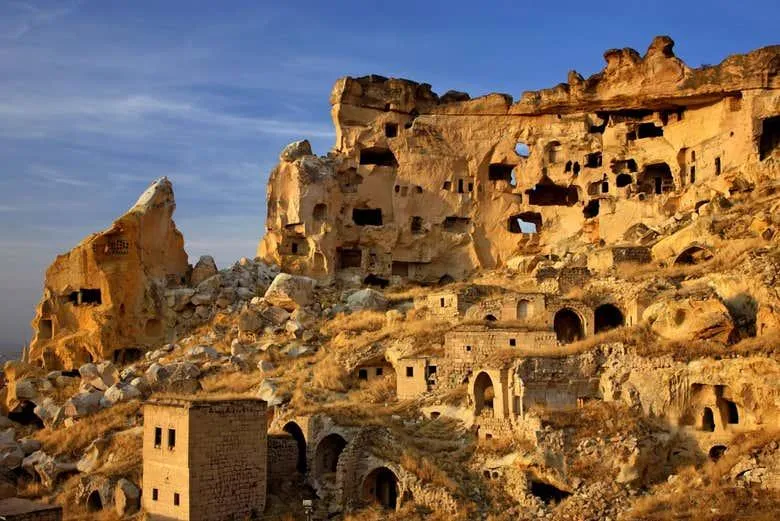Cave houses carved into the cliff of old Çavuşin at sunset