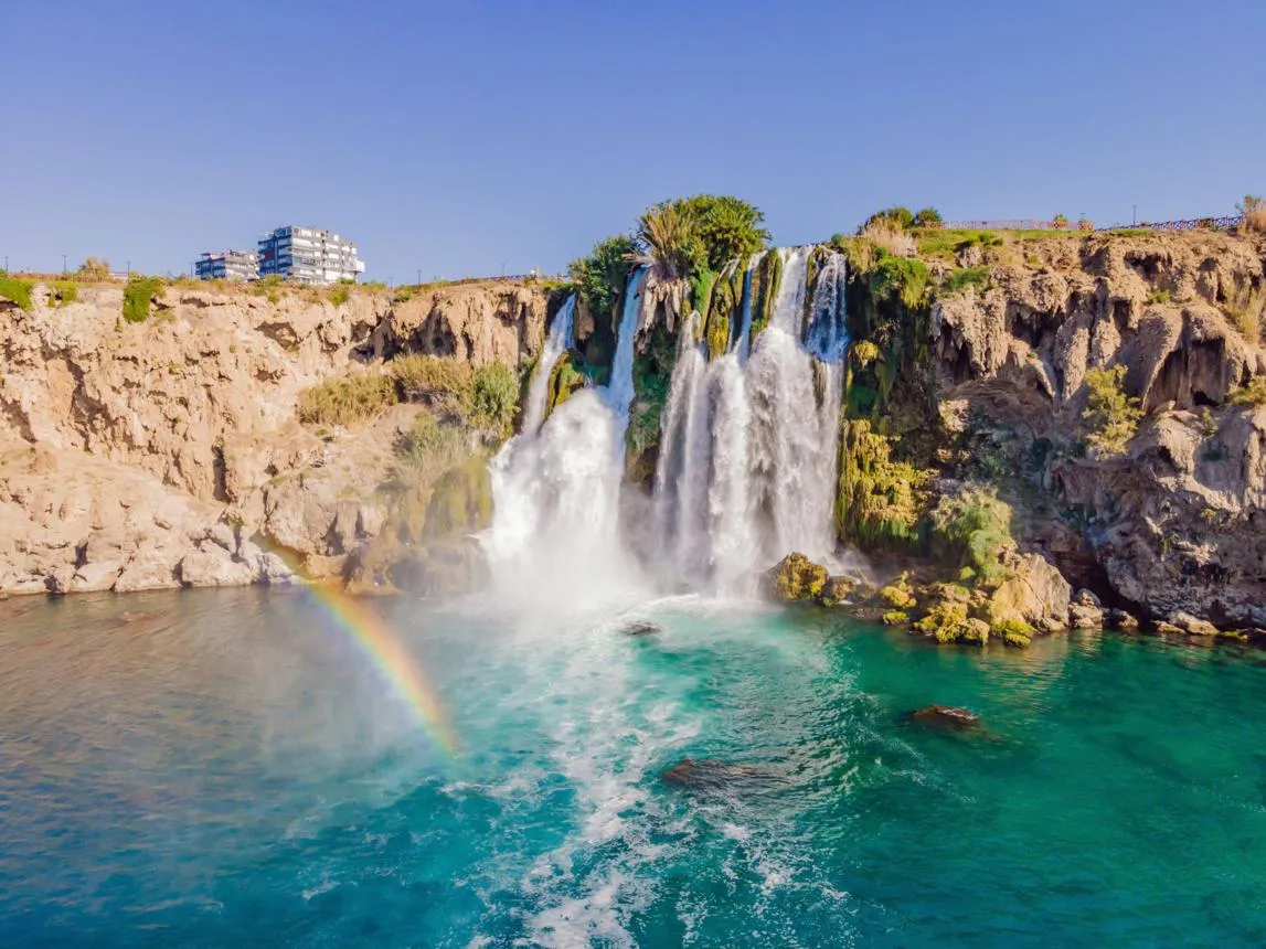 The Lower Düden Waterfall pouring from the cliffs into the sea with a rainbow