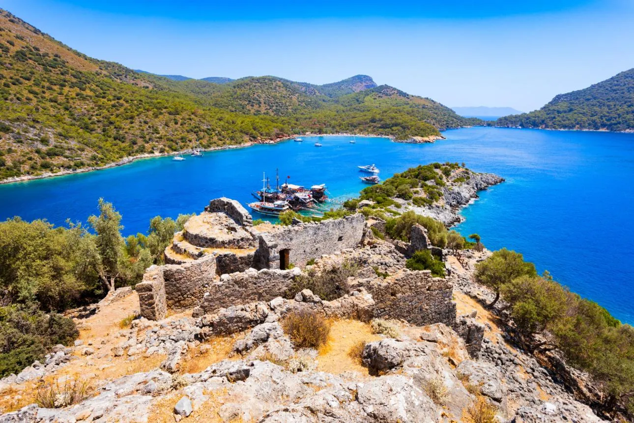Byzantine church ruins on Gemiler Island above a bay with boats