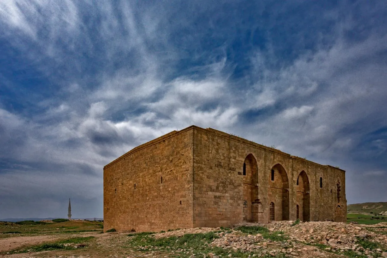 The stone walls and arched windows of Germüş Church under a dramatic sky
