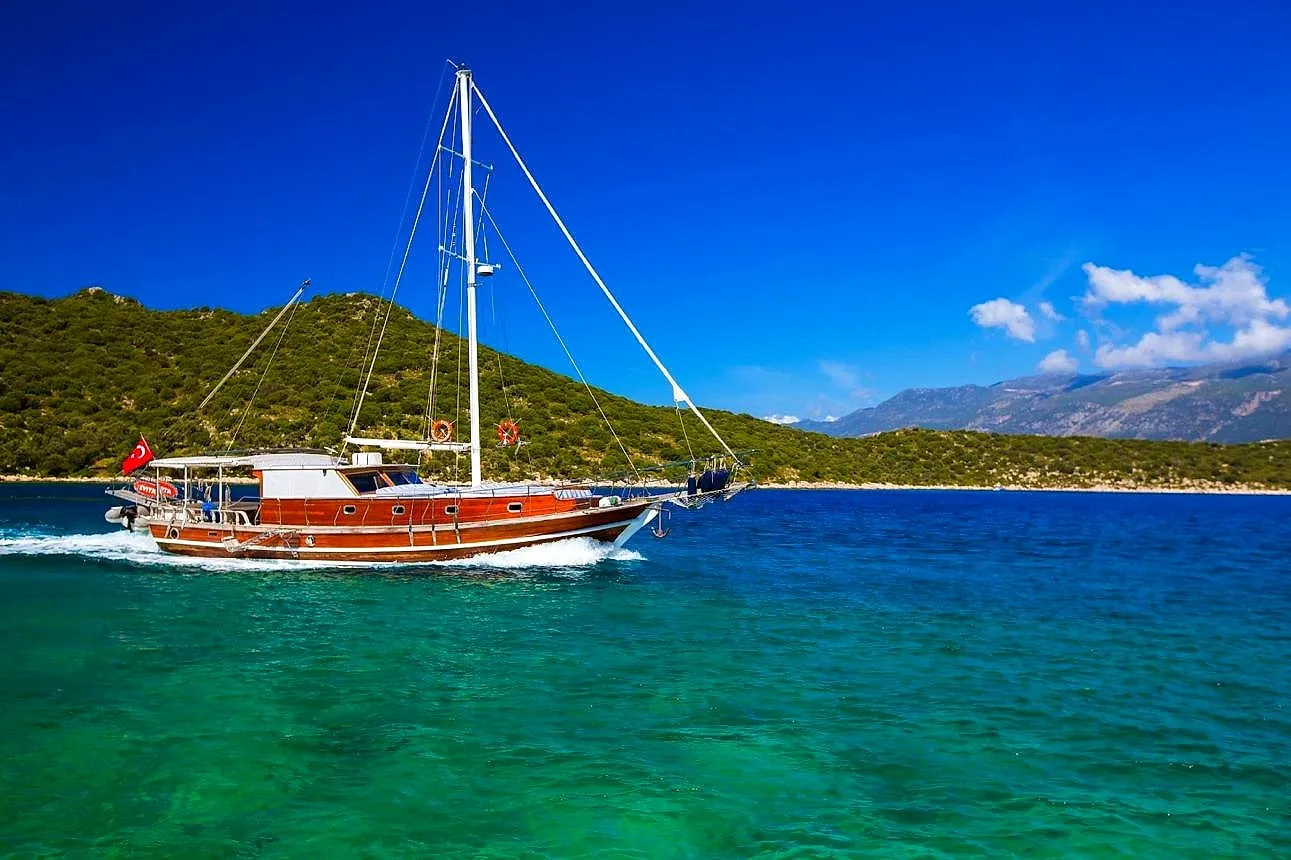 A wooden gulet under sail on turquoise water
