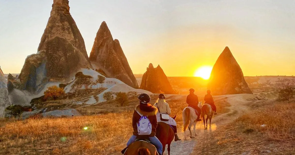 Riders on horseback among fairy chimneys at sunset