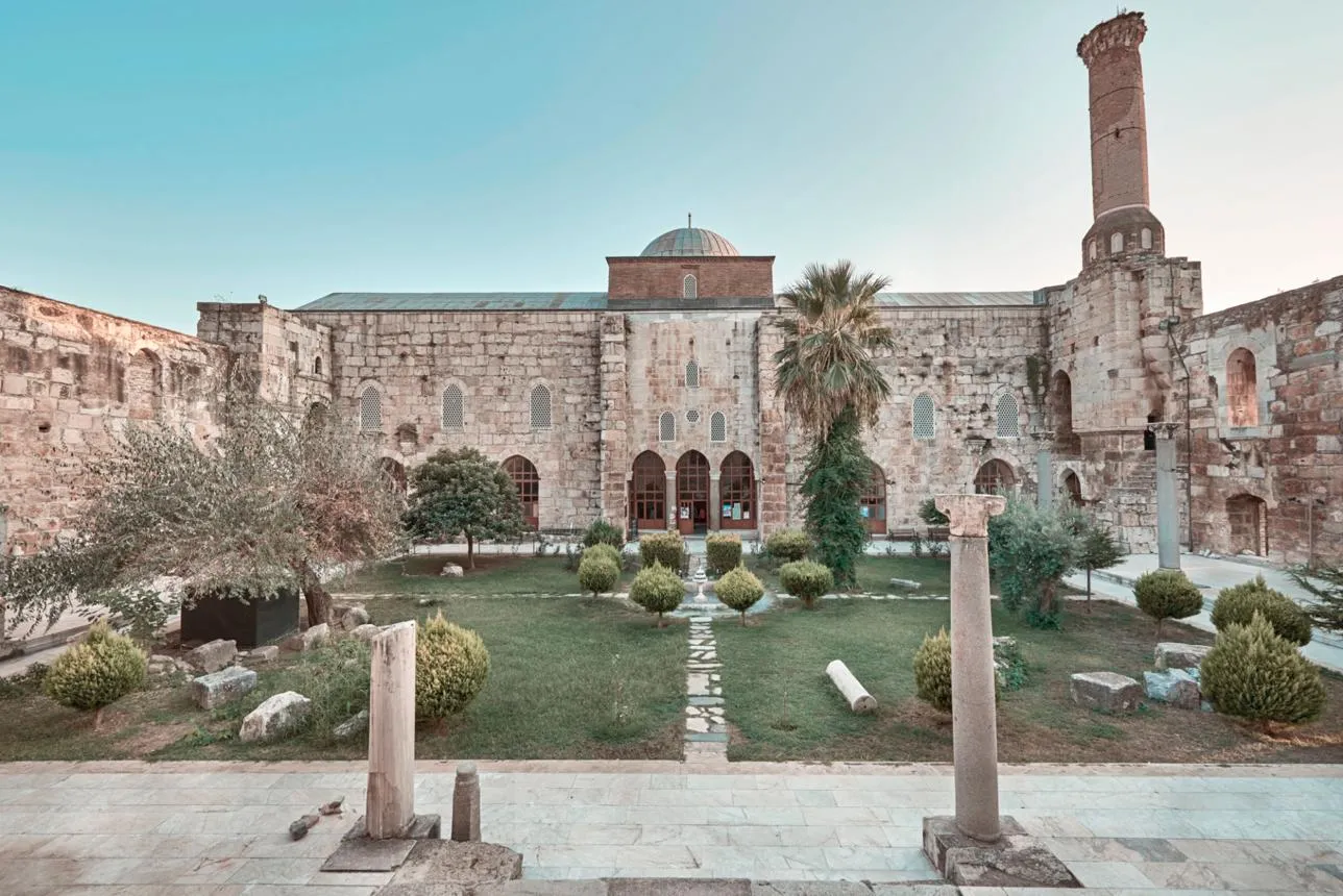 Stone walls, dome and brick minaret of the İsa Bey Mosque