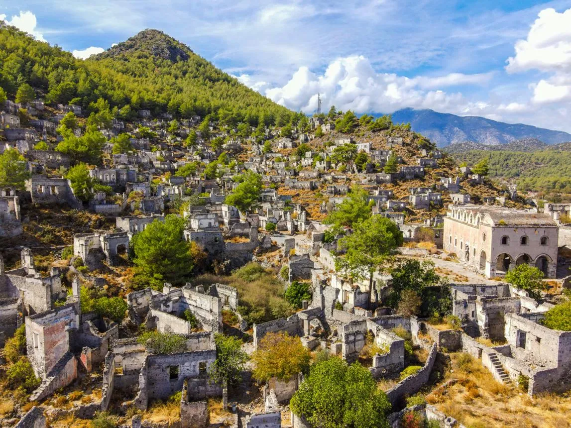 Hundreds of roofless stone houses of Kayaköy on a green hillside