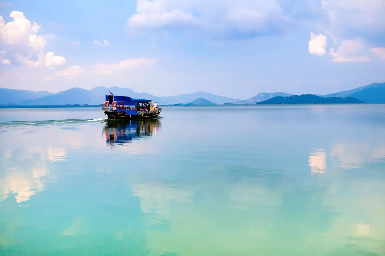 A boat crossing the calm water of Lake Köyceğiz below distant mountains