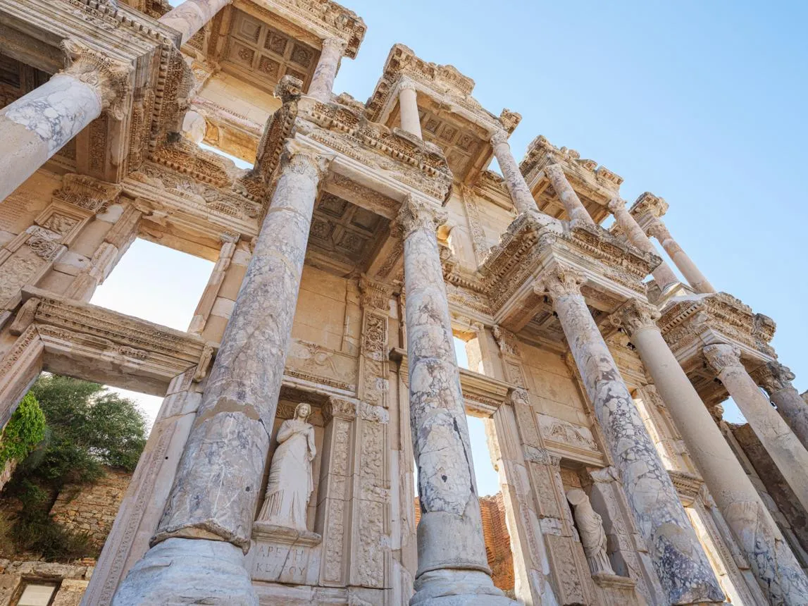 Looking up at the marble columns and statues of the Library of Celsus