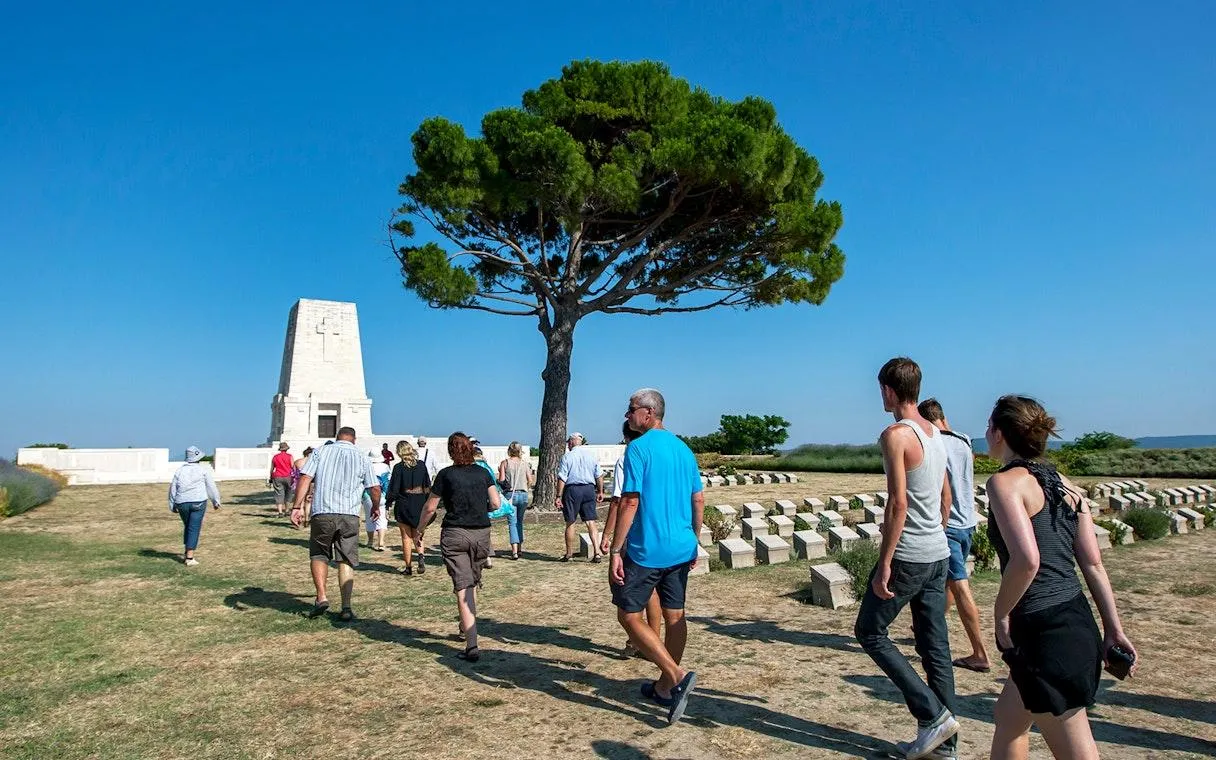 Visitors walking towards the Lone Pine memorial beside a lone pine tree
