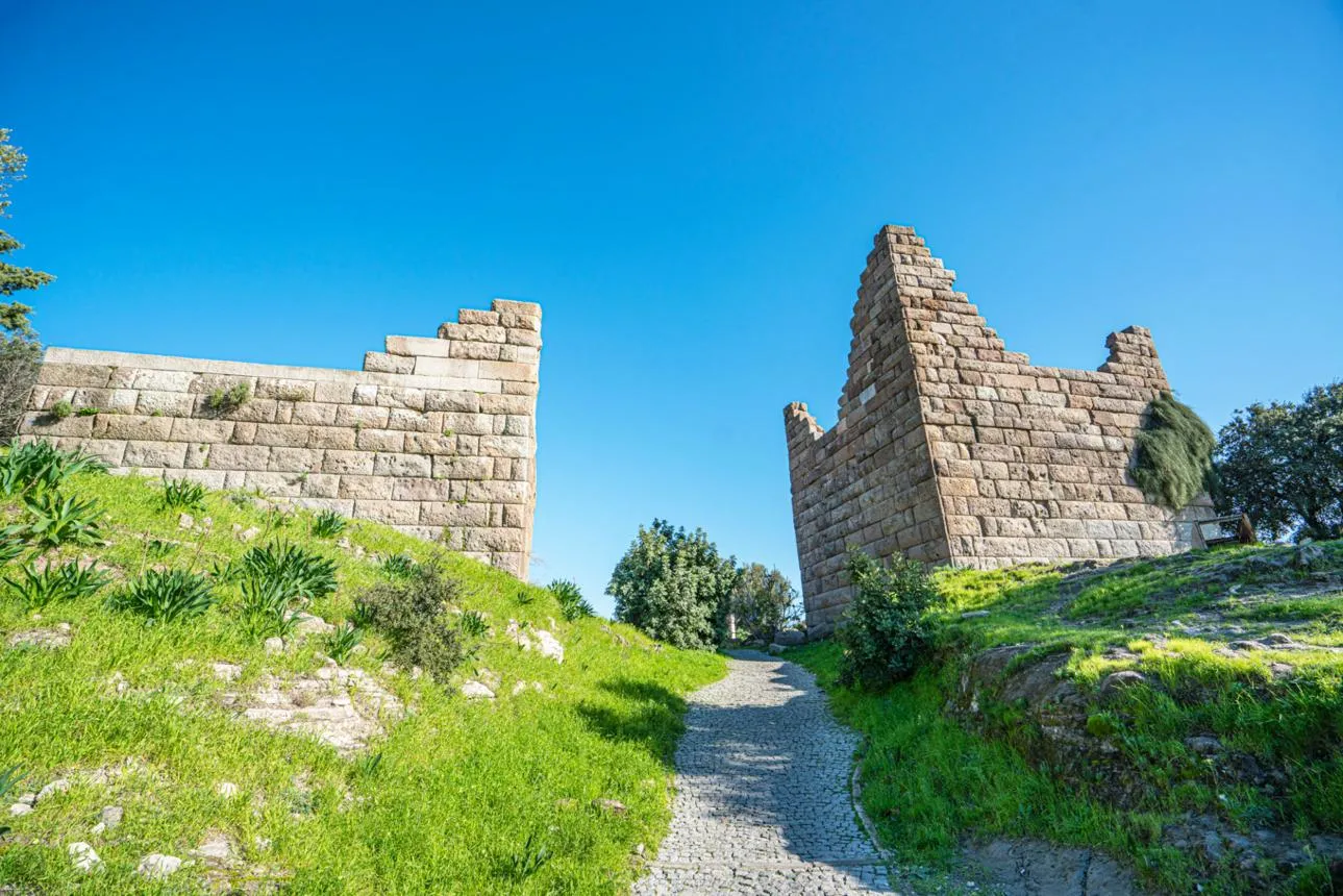 The two stone towers of Myndos Gate on a green hillside