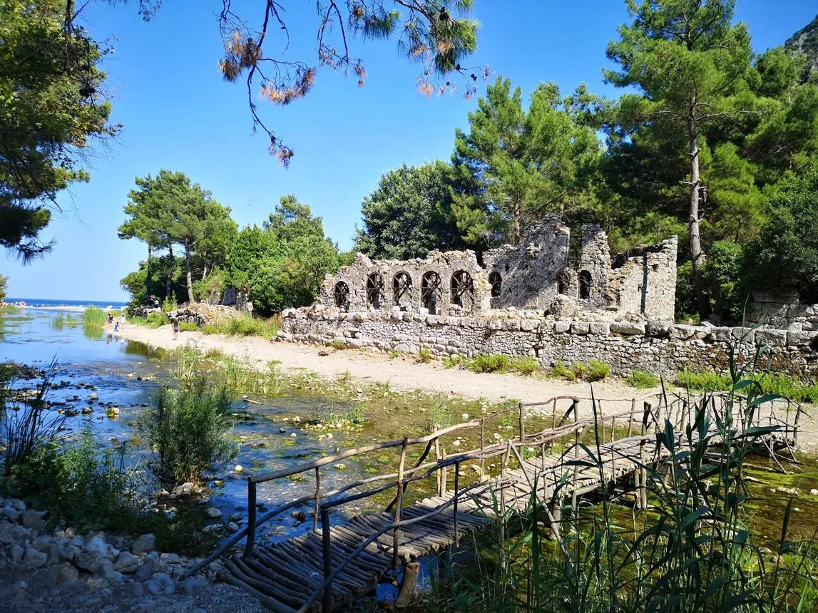 Ruined stone walls of Olympos beside a stream in a wooded valley