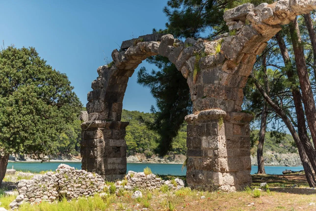 A ruined aqueduct arch among pine trees by the sea at Phaselis