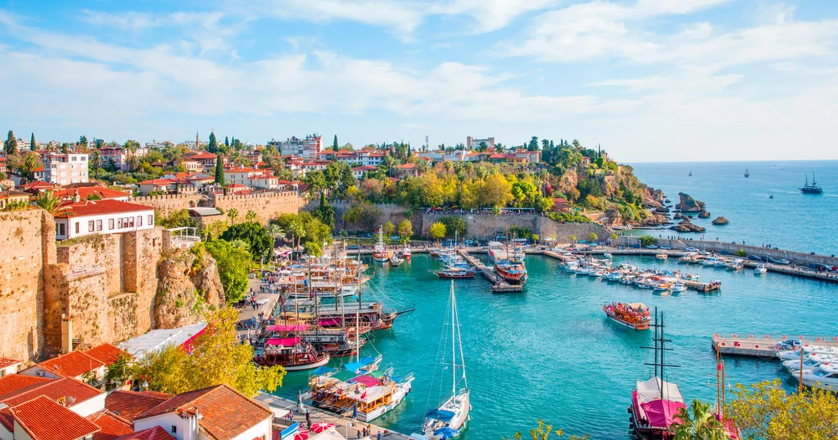 Kaleiçi's harbour full of wooden boats below the old town walls and cliffs