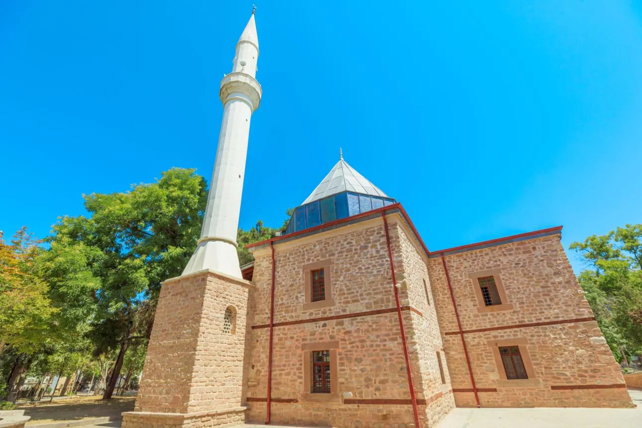 The stone mosque and white minaret of Şems-i Tebrizi among trees