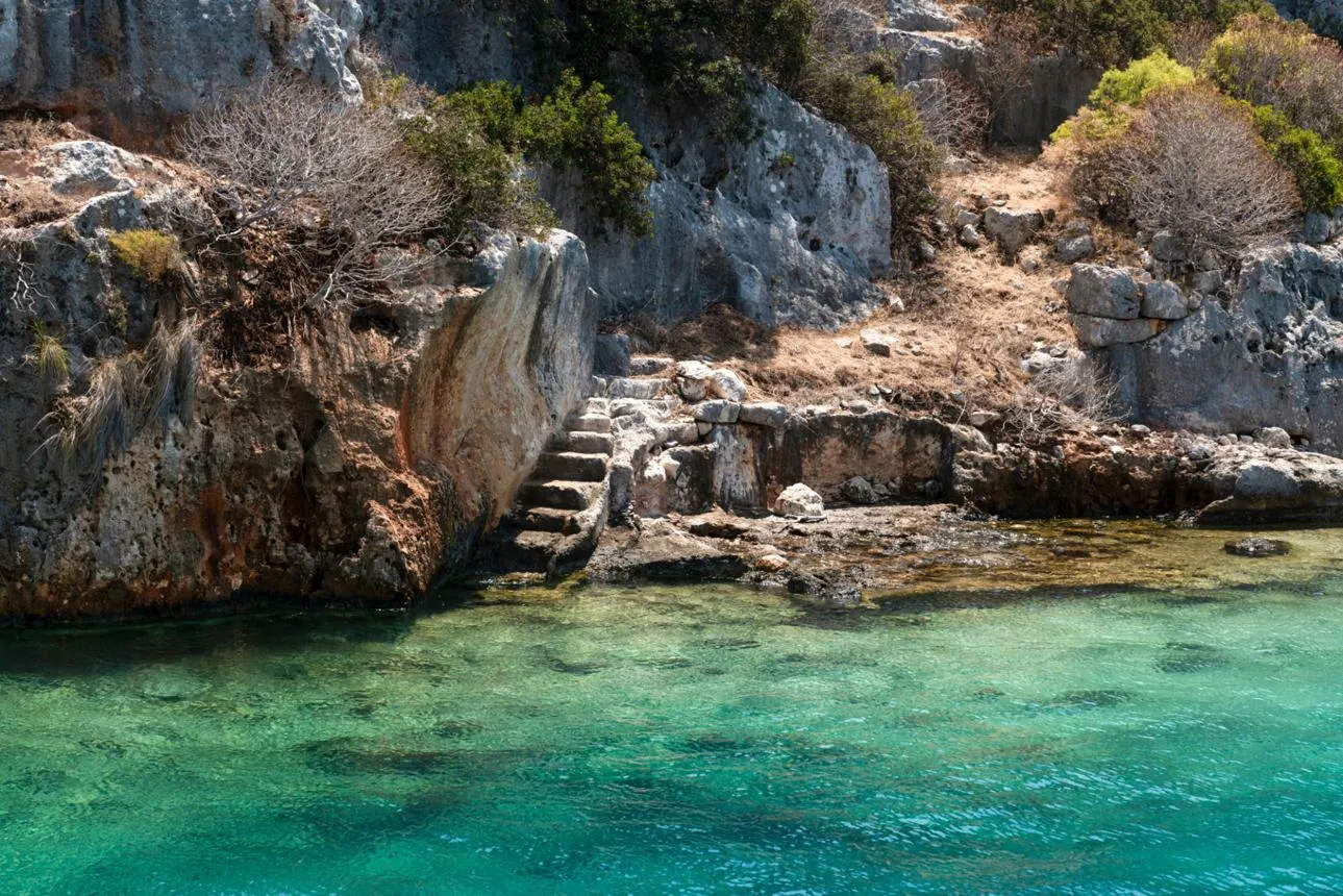 Ancient stone steps and walls running down into the clear water of Kekova