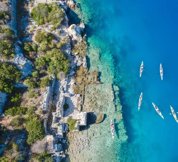 Aerial view of the ruins and clear water at Tersane Bay with kayaks offshore