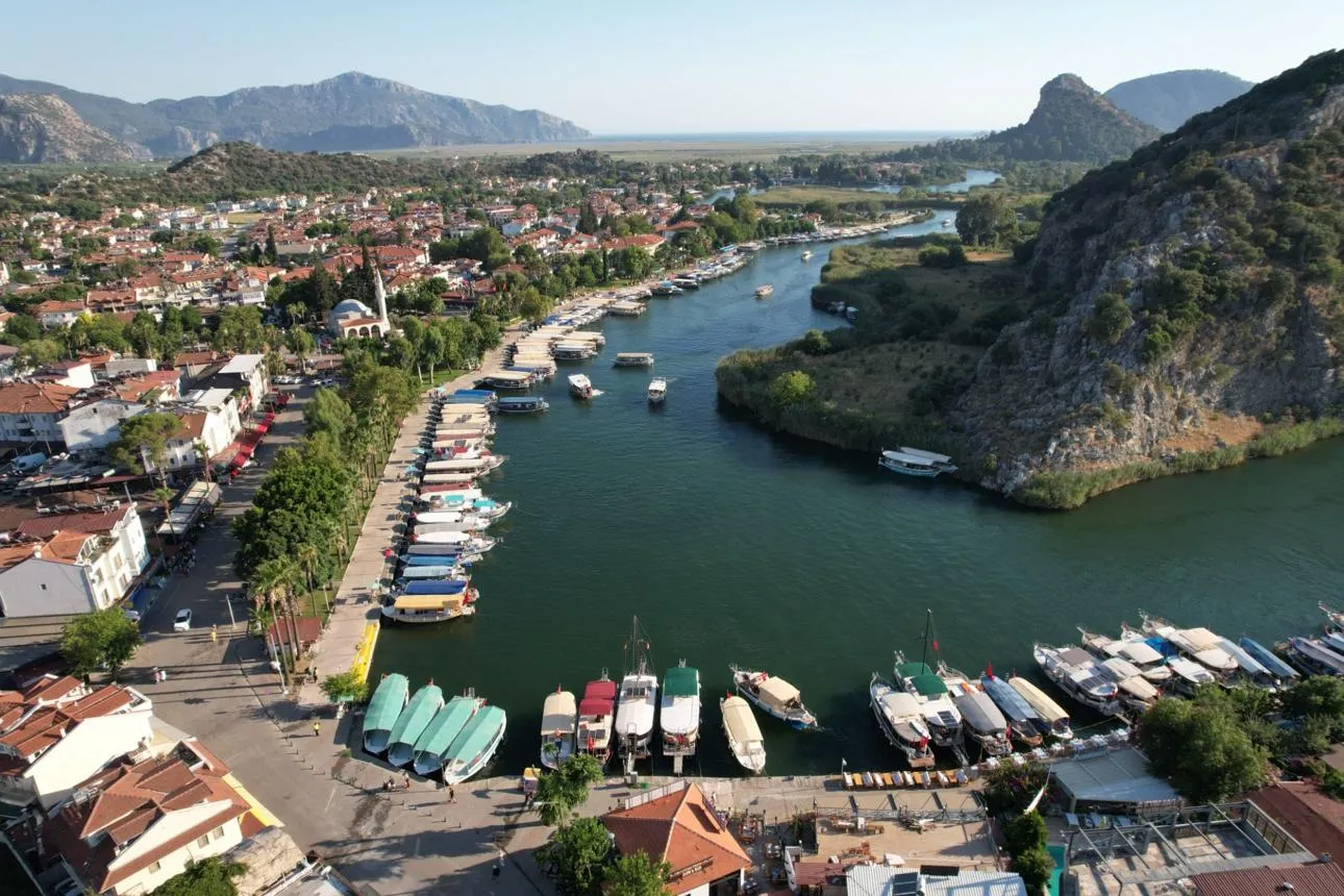 Dalyan's riverside quay lined with boats below the cliffs
