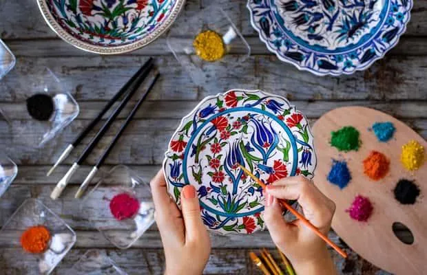 Hands painting a traditional Turkish ceramic plate