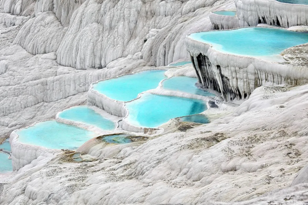 Shallow turquoise pools stepping down the white travertine terraces