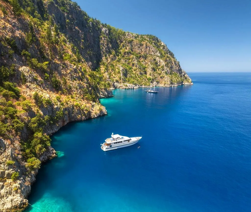 A private yacht in a turquoise cove below the cliffs