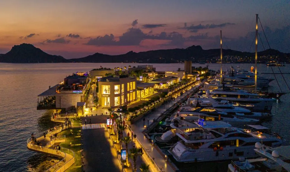Yalıkavak marina, its shops and superyachts lit up at dusk