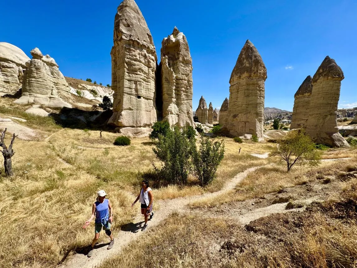 Two walkers on a trail among fairy chimneys in Zemi Valley
